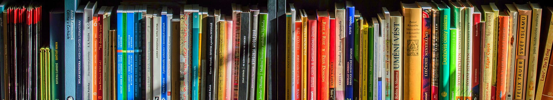 En hylla fylld med böcker i olika storlekar och färger stående tätt tillsammans.